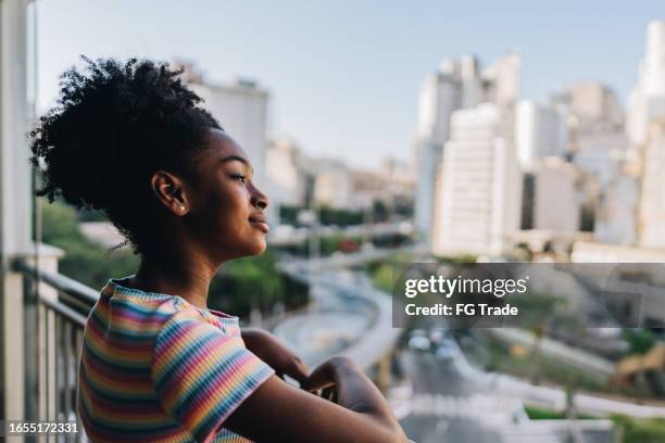 muchacha contemplando en el balcón del apartamento - mirar alrededor fotografías e imágenes de stock