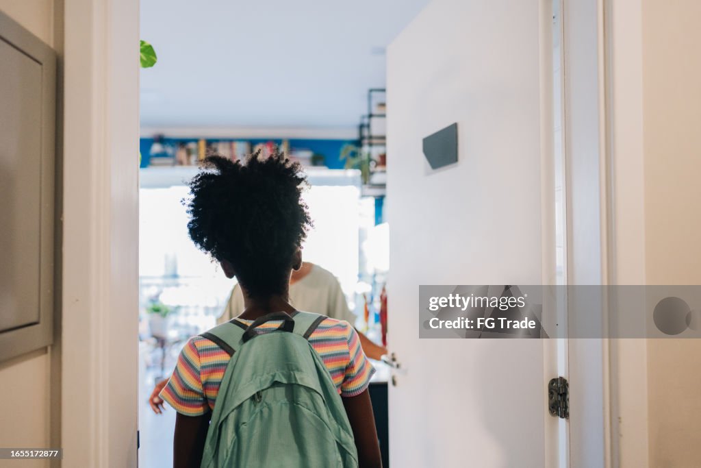 Vista trasera de una estudiante que llega a casa