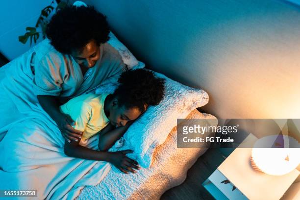 mother looking her daughter while she's sleeping in the bedroom at home - bedside table kid asleep stock pictures, royalty-free photos & images