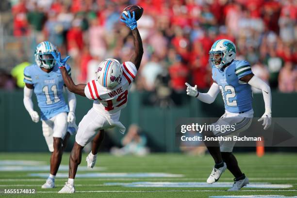 Dayton Wade of the Mississippi Rebels catches the ball as Bailey Despanie and A.J. Hampton Jr. #11 of the Tulane Green Wave defend during the second...