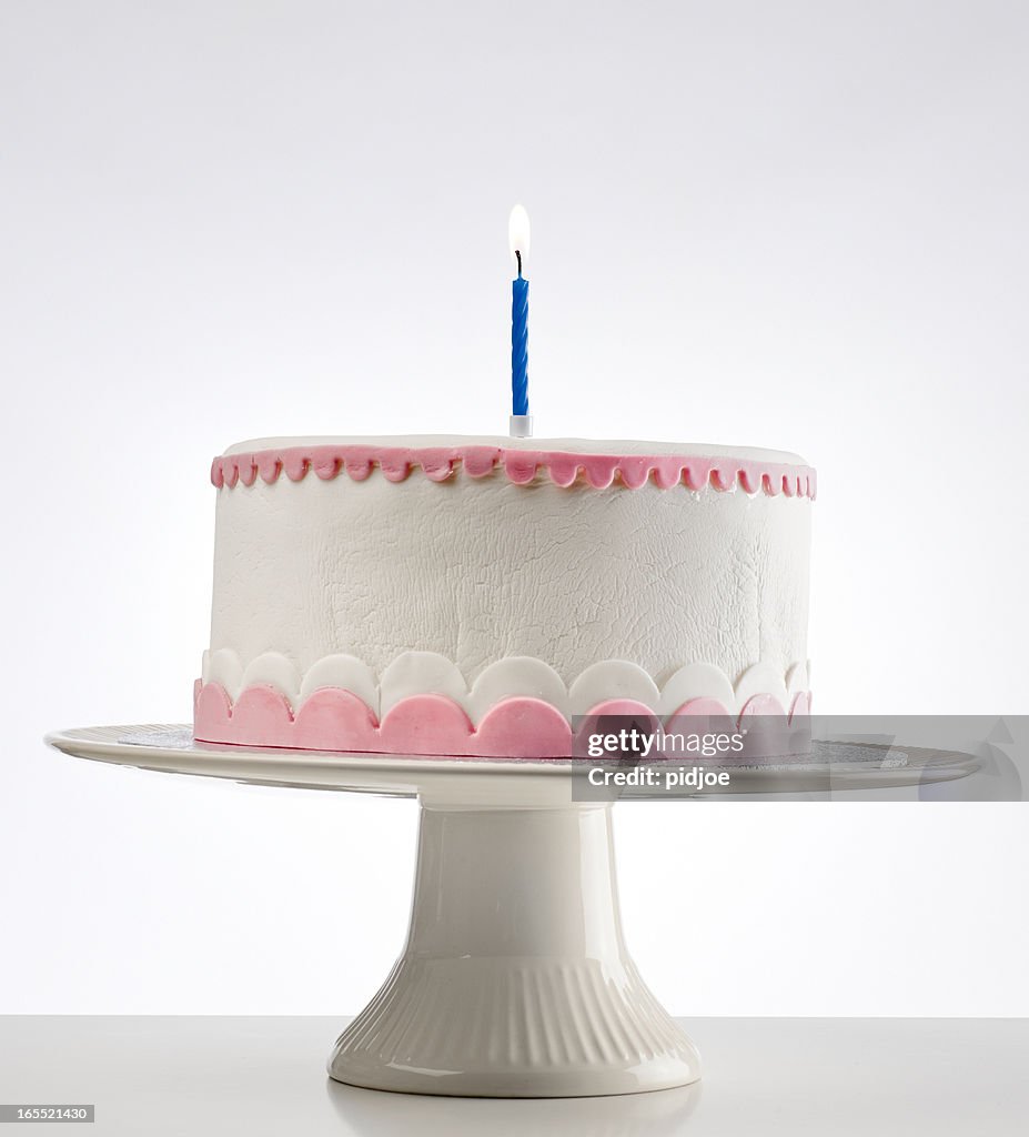 Birthday cake on cakestand with one burning candle