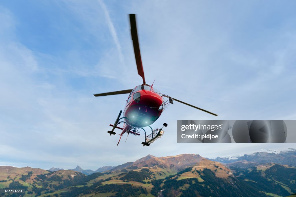 Red rescue helicopter landing on mountain