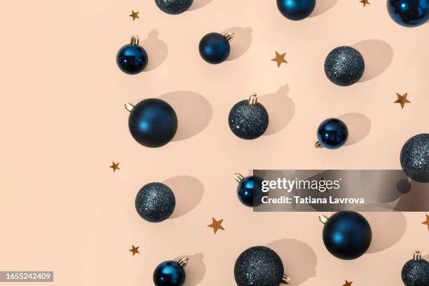 beautiful shiny blue baubles on beige background with golden glittering stars and copy space for text. festive xmas backdrop with christmas toys on table - blue baubles stock-fotos und bilder