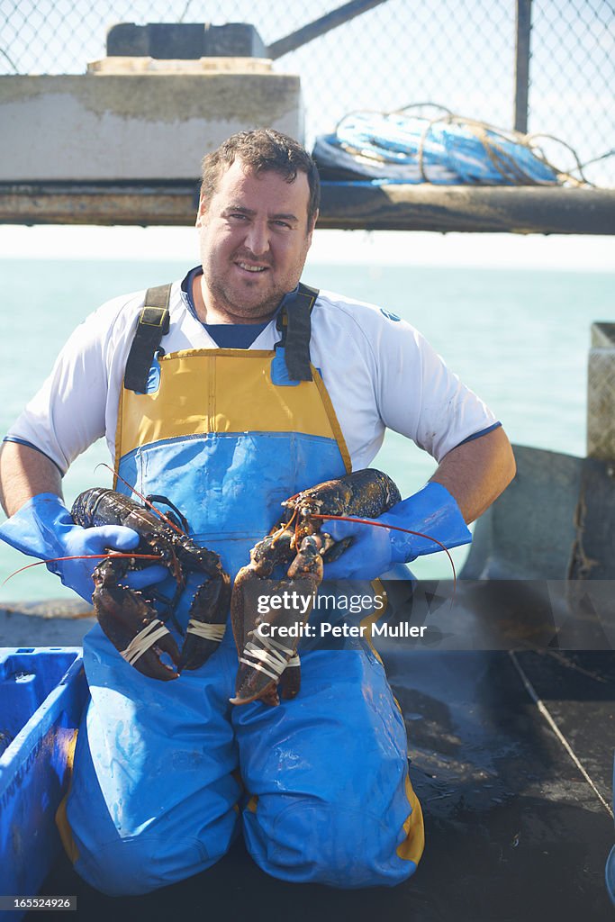 Fisherman holding lobsters on boat