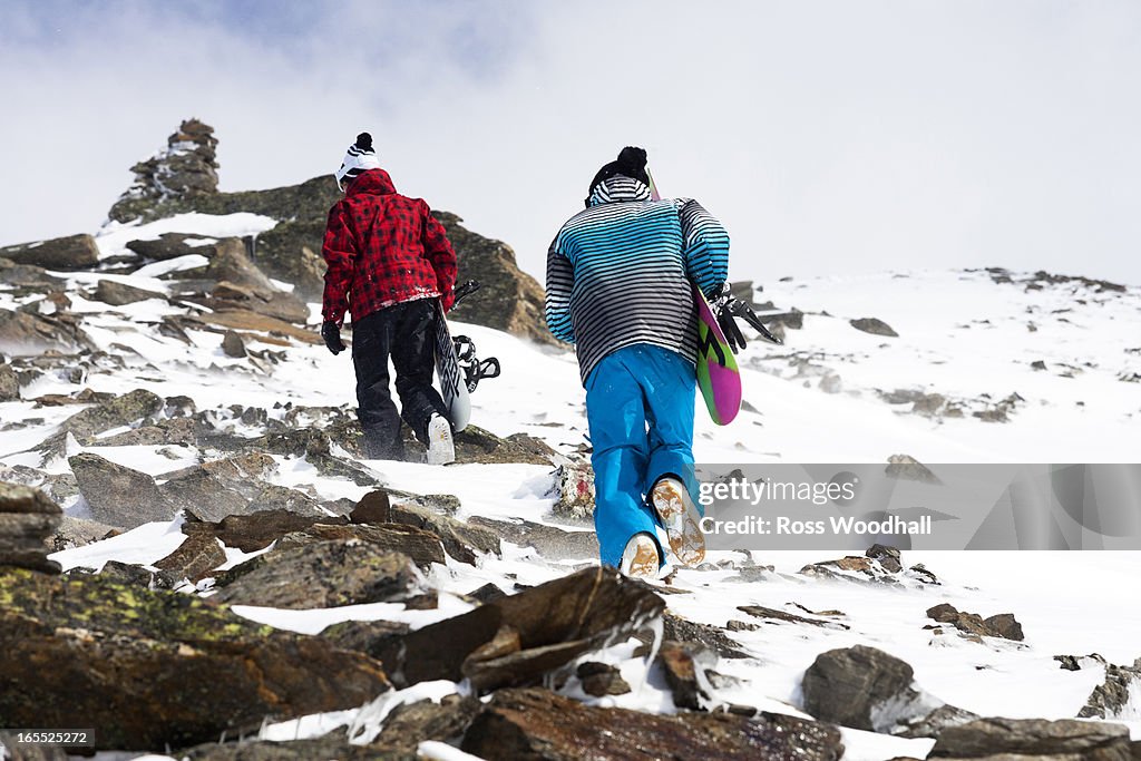 Snowboarders hiking on rocky slope