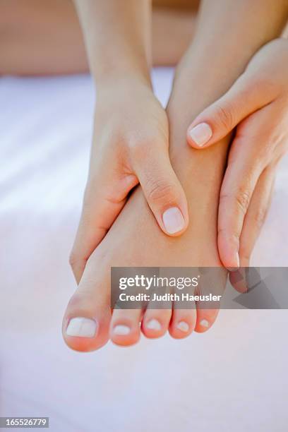 close up of woman rubbing her foot - his foot stockfoto's en -beelden
