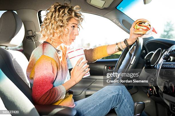 eating fast food hamburgers and driving. - woman eating burger stockfoto's en -beelden