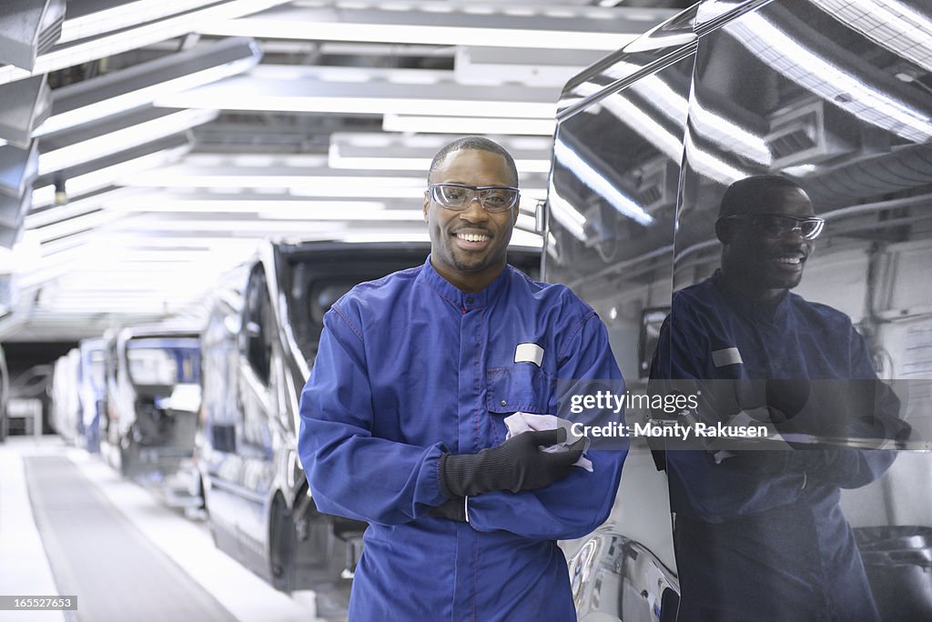 Portrait of worker wearing boiler suit and protective goggles in car factory