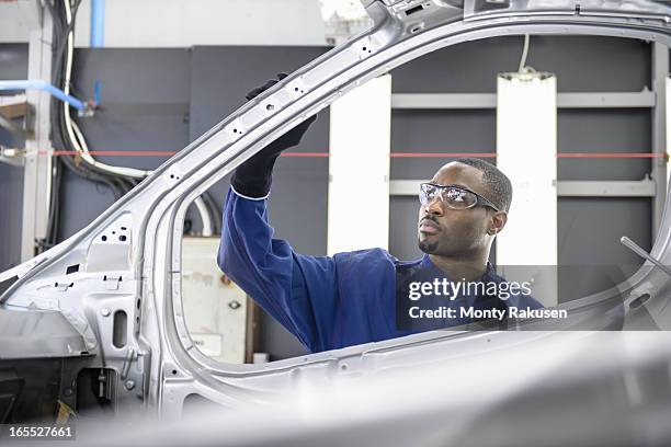 worker inspecting paint finish in car factory - automobilbau stock-fotos und bilder