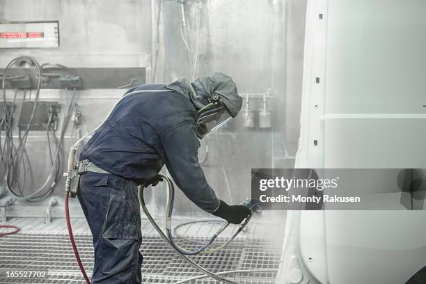 worker wearing protective suit and mask spray painting van body in car factory - 車　作業員 ストックフォトと画像