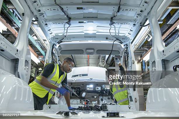 car workers wearing high visibility jackets fitting parts on vehicle on production line in car factory - automobile production at the seat factory stock pictures, royalty-free photos & images