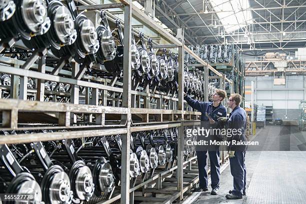 workers inspecting large number of axles on shelving unit in car plant - automotive plant stock pictures, royalty-free photos & images