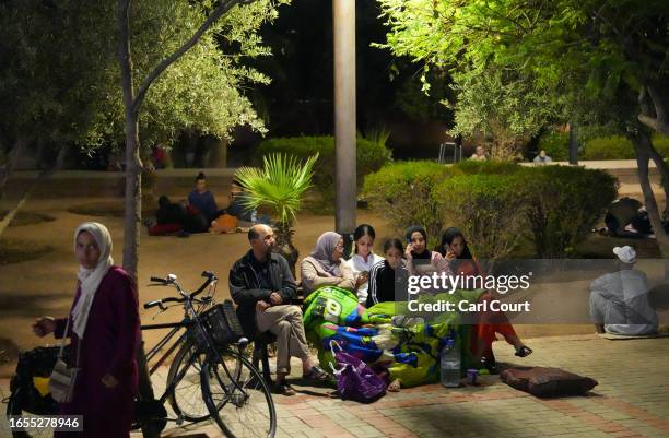 People sit under a blanket on a bench in a park after being made homeless by an earthquake on September 9, 2023 in Marrakech, Morocco. An earthquake...