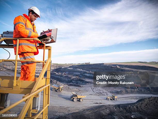 ecologist using digital tablet surveying surface coal mine site from platform, elevated view - mining low angle foto e immagini stock