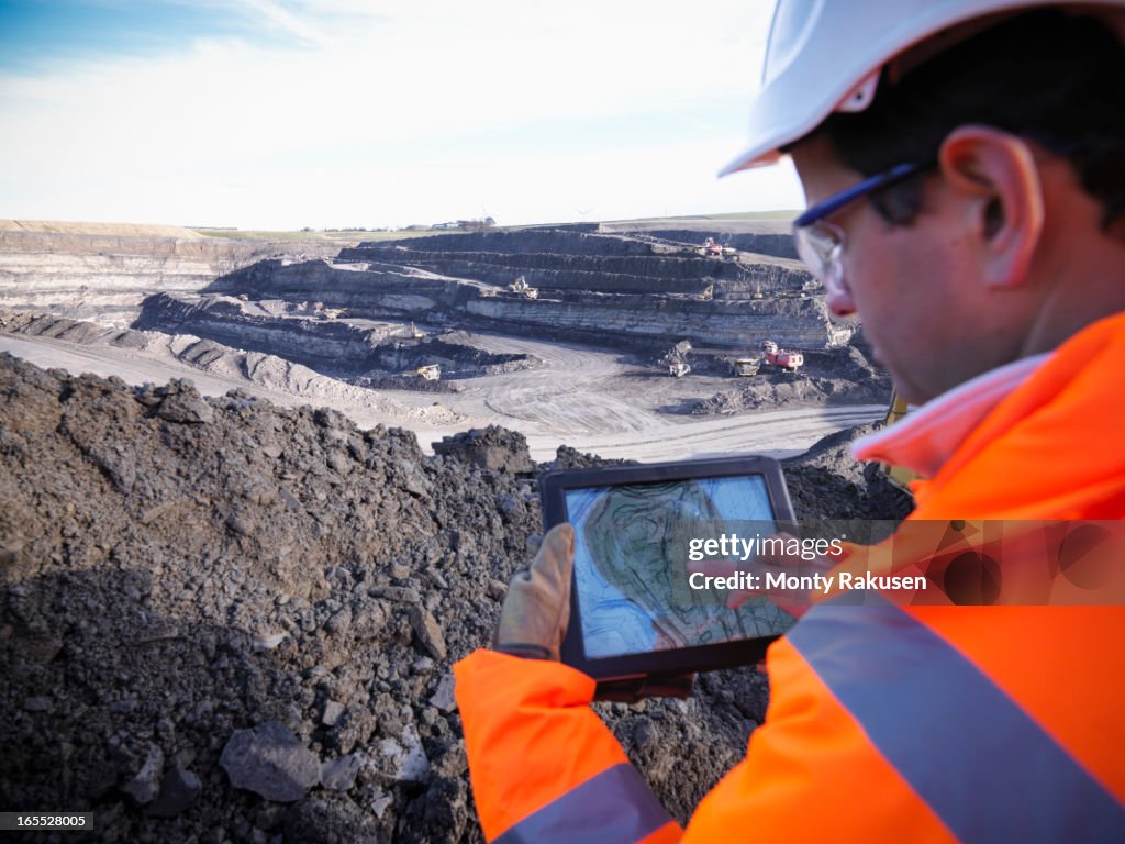 Ecologist using digital tablet surveying surface coal mine site, elevated view