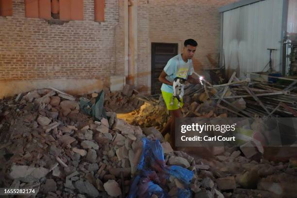 Man carries a cat through the rubble of a partially collapsed mosque on September 9, 2023 in Marrakech, Morocco. An earthquake measuring 6.8 on the...