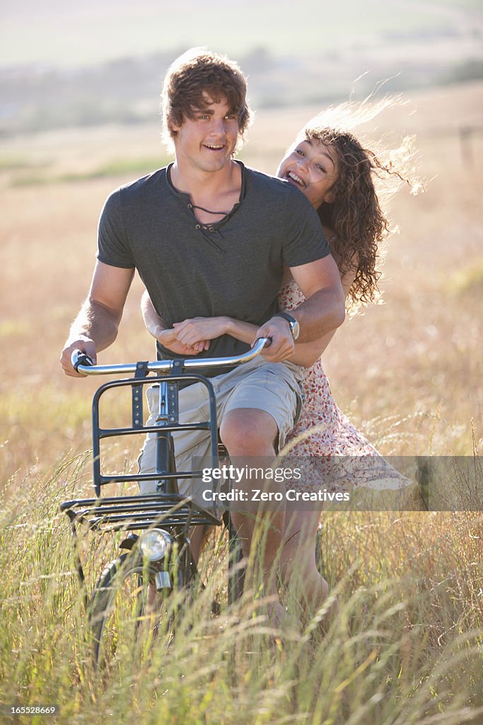 Couple riding bicycle in tall grass