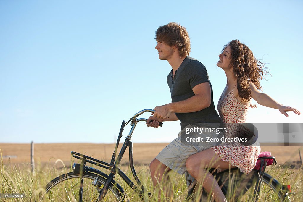 Couple riding bicycle in tall grass