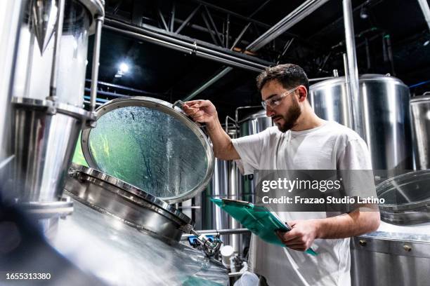 mid adult man analyzing a beer production machine in a brewery - brewery stock pictures, royalty-free photos & images