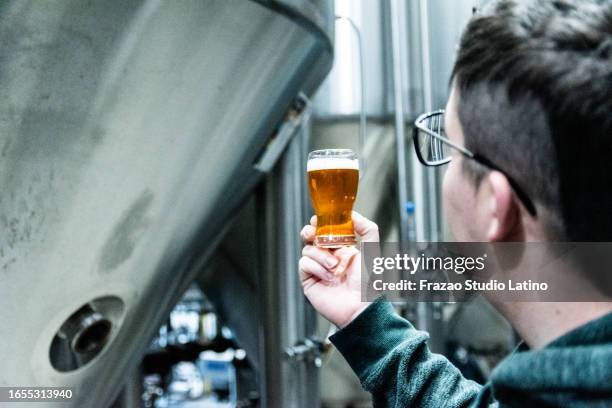 close-up of a mid adult man holding a beer glass in a brewery - microbrewery stock pictures, royalty-free photos & images
