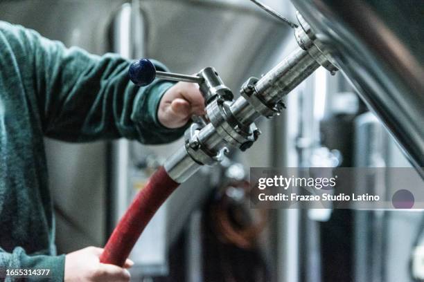 close-up of human hand putting the hose on machine on a brewery - hose stock pictures, royalty-free photos & images