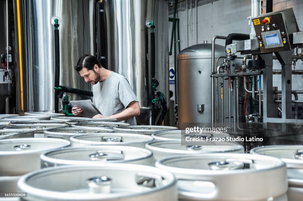 Mid adult man analyzing the beer barrels in a brewery