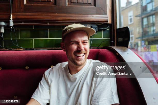 young man with cap relaxing in an establishment - junger mann allein stock-fotos und bilder