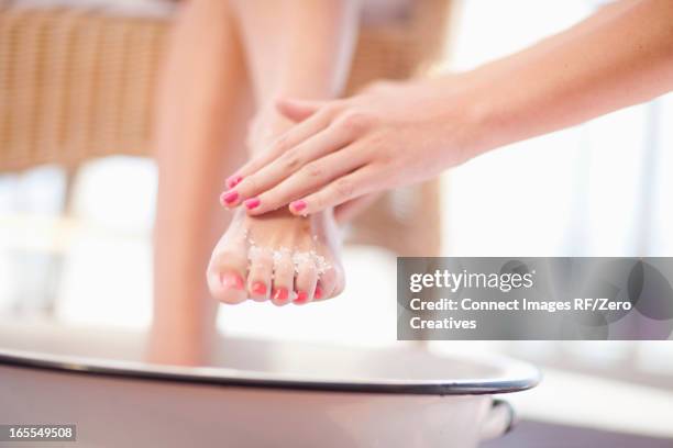 woman having salt scrub on feet - esfoliazione foto e immagini stock