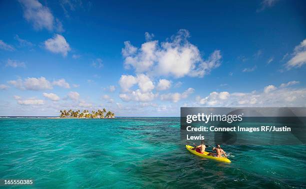 people rowing canoe in tropical water - kayaking beach stock pictures, royalty-free photos & images