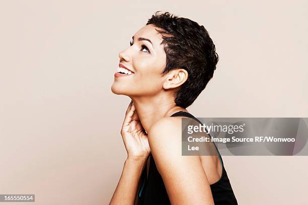 smiling woman standing indoors - woman looking up sideview stock-fotos und bilder