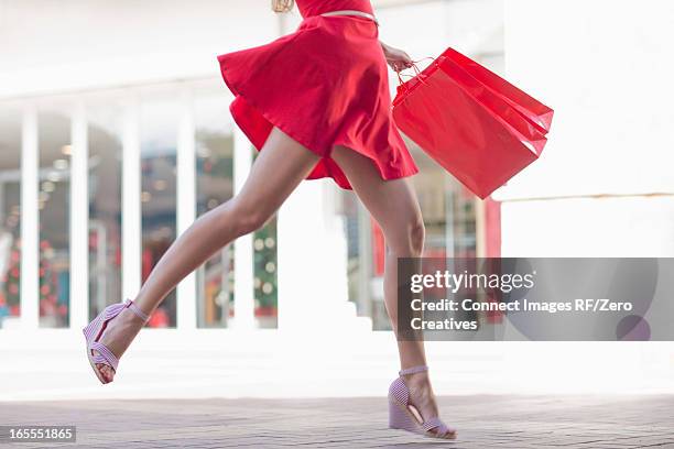 woman carrying shopping bag outdoors - rotes kleid stock-fotos und bilder