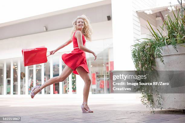 woman carrying shopping bag outdoors - red dress stock pictures, royalty-free photos & images