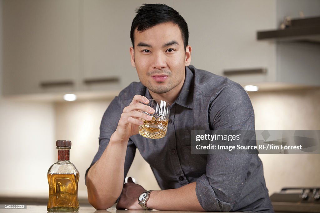 Man having glass of whiskey in kitchen