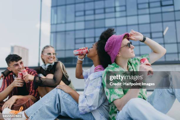 diverse group of generation z friends hanging out together, drinking soda from cans in the city. - energydrink stock-fotos und bilder