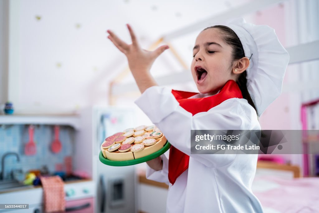 Child girl singing while hold a sweet pie in the bedroom at home