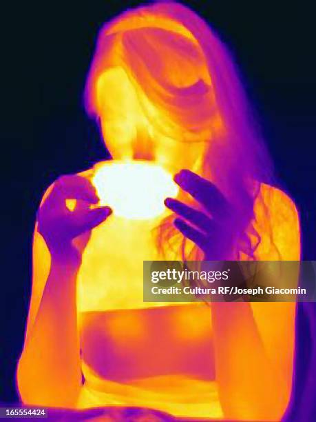 thermal image of woman having cup of tea - thermo becher stock-fotos und bilder