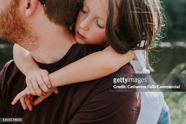 a daughter drapes her arms lovingly around her father's neck - affectionate fotografías e imágenes de stock