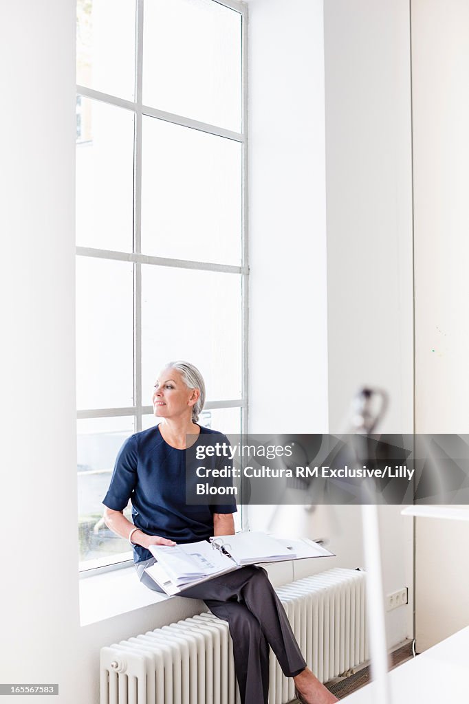 Businesswoman reading in windowsill