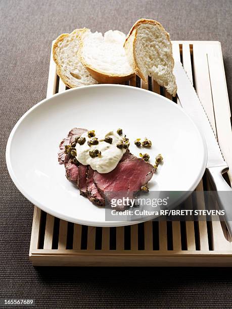 plate of veal fillet with capers - bread knife stock-fotos und bilder