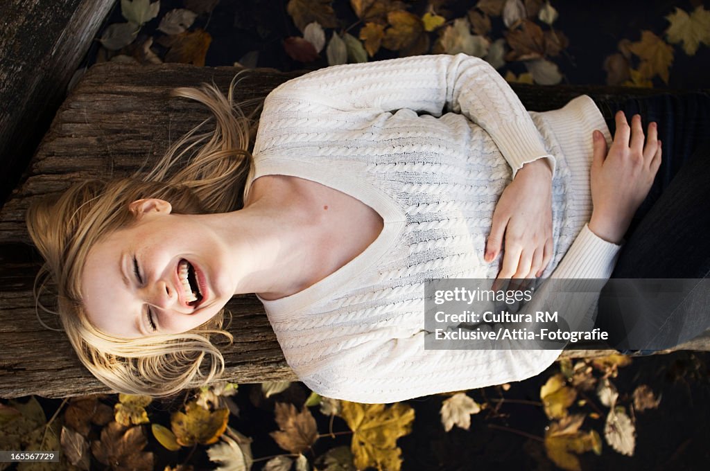 Woman laying on log in autumn leaves
