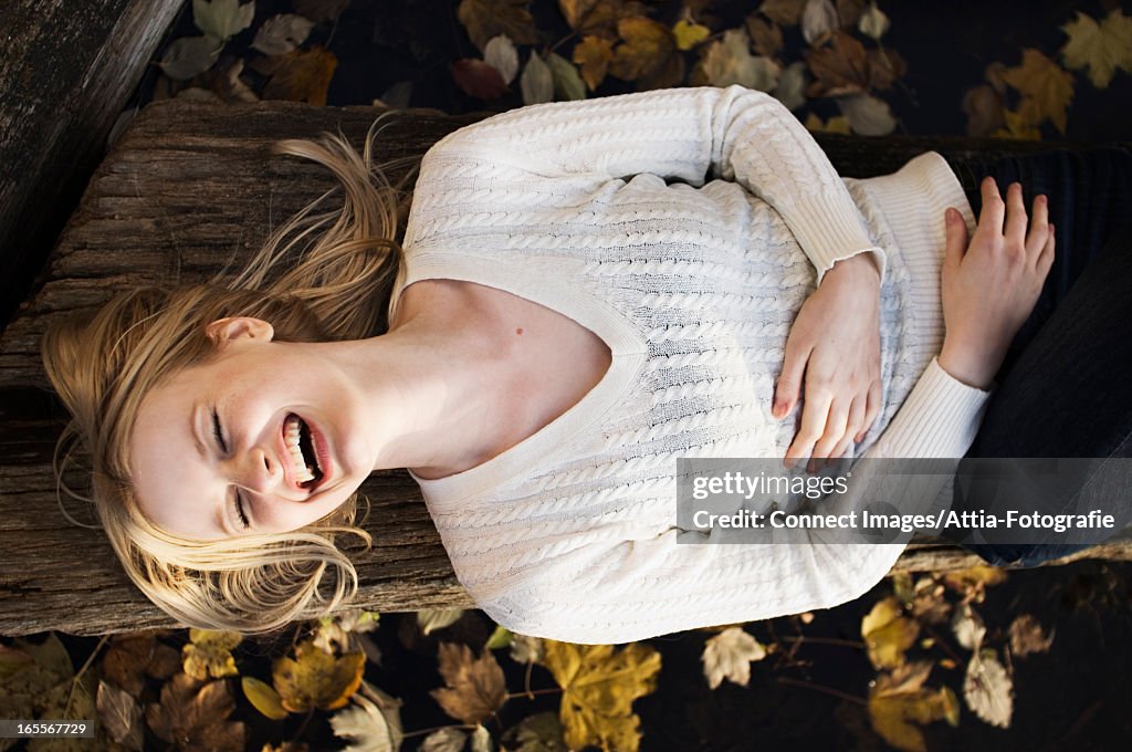 Woman laying on log in autumn leaves