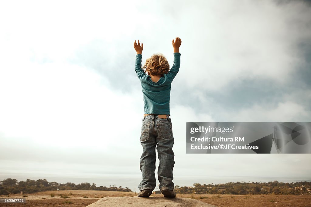 Boy cheering on dirt road