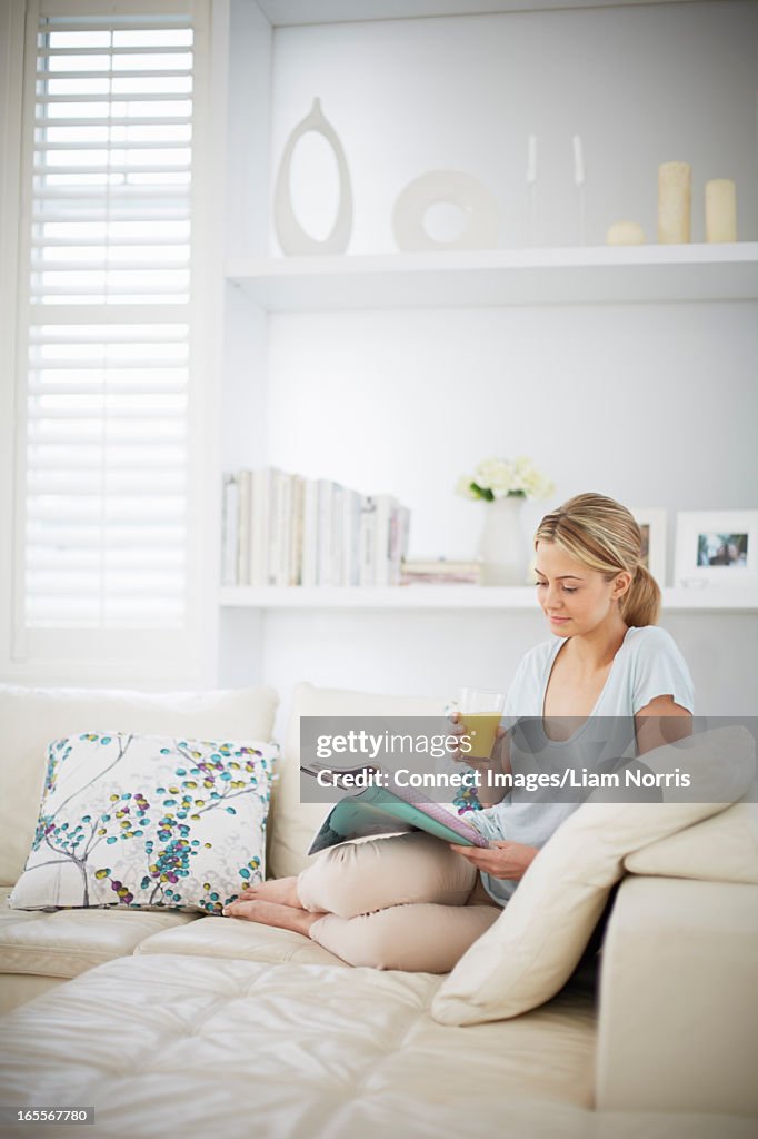 Woman reading magazine on sofa