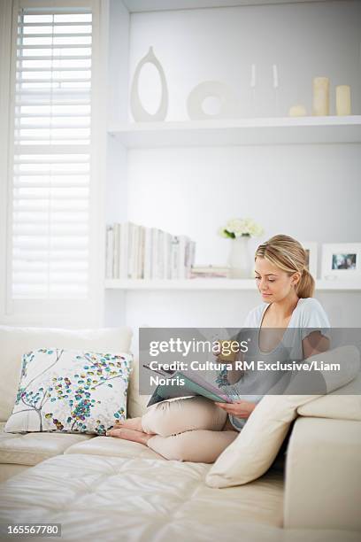 woman reading magazine on sofa - diet journal - fotografias e filmes do acervo