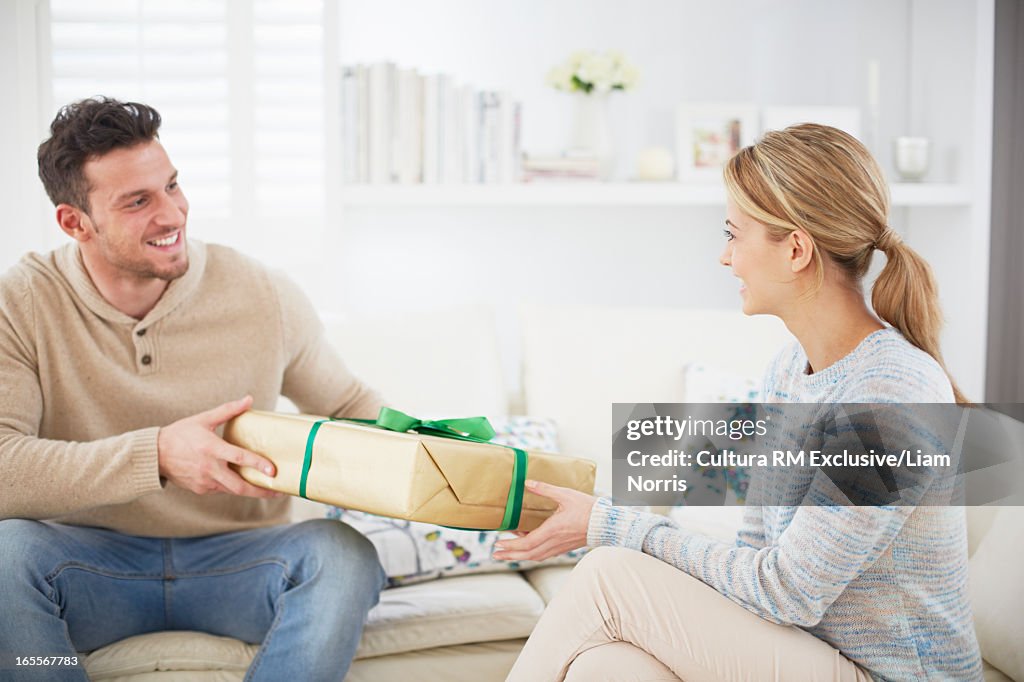 Man giving girlfriend gift on sofa