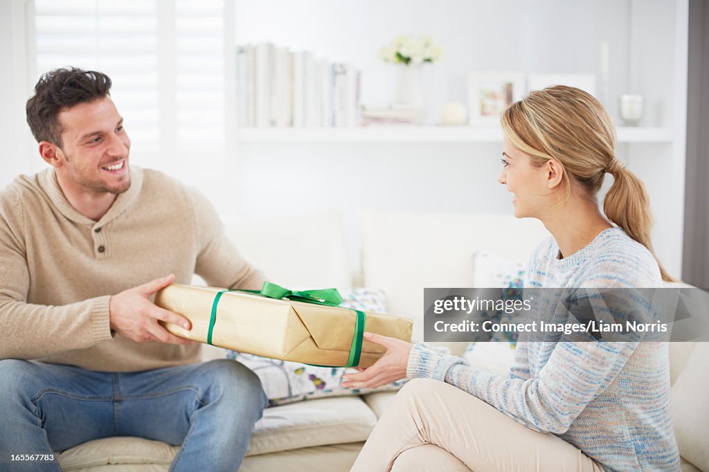 Man giving girlfriend gift on sofa