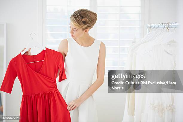 woman selecting red dress in bedroom - red dress stock-fotos und bilder
