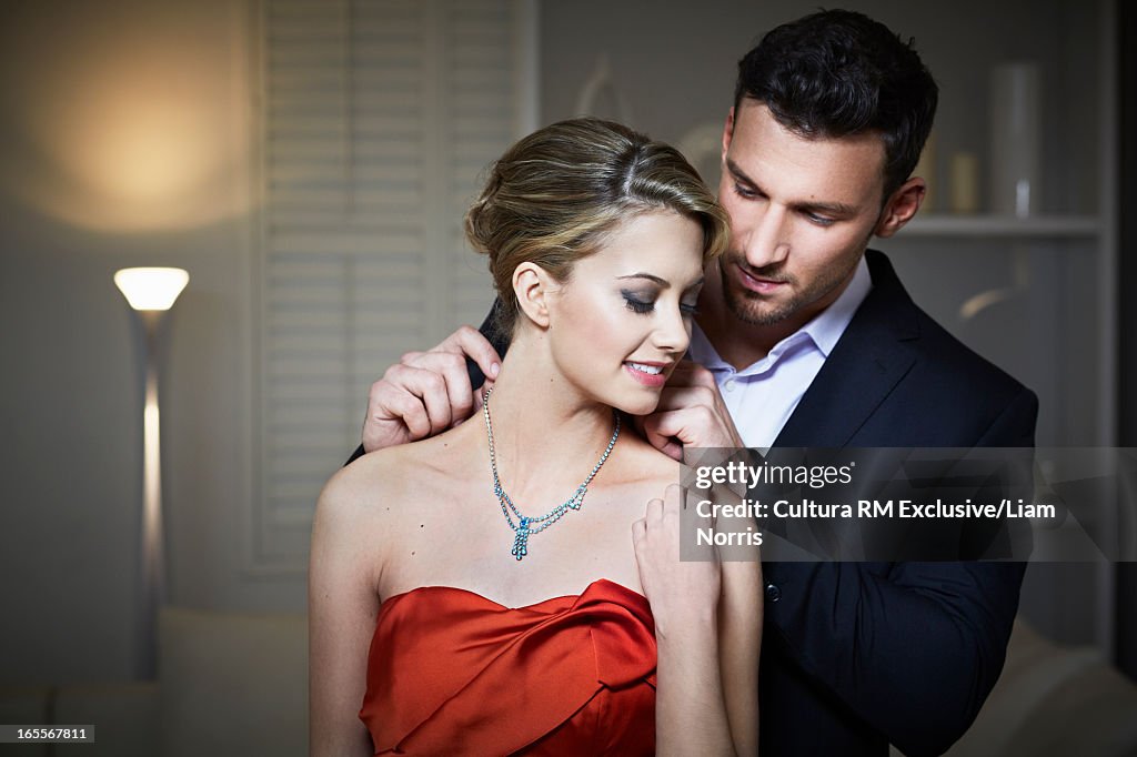 Man tying necklace on girlfriend