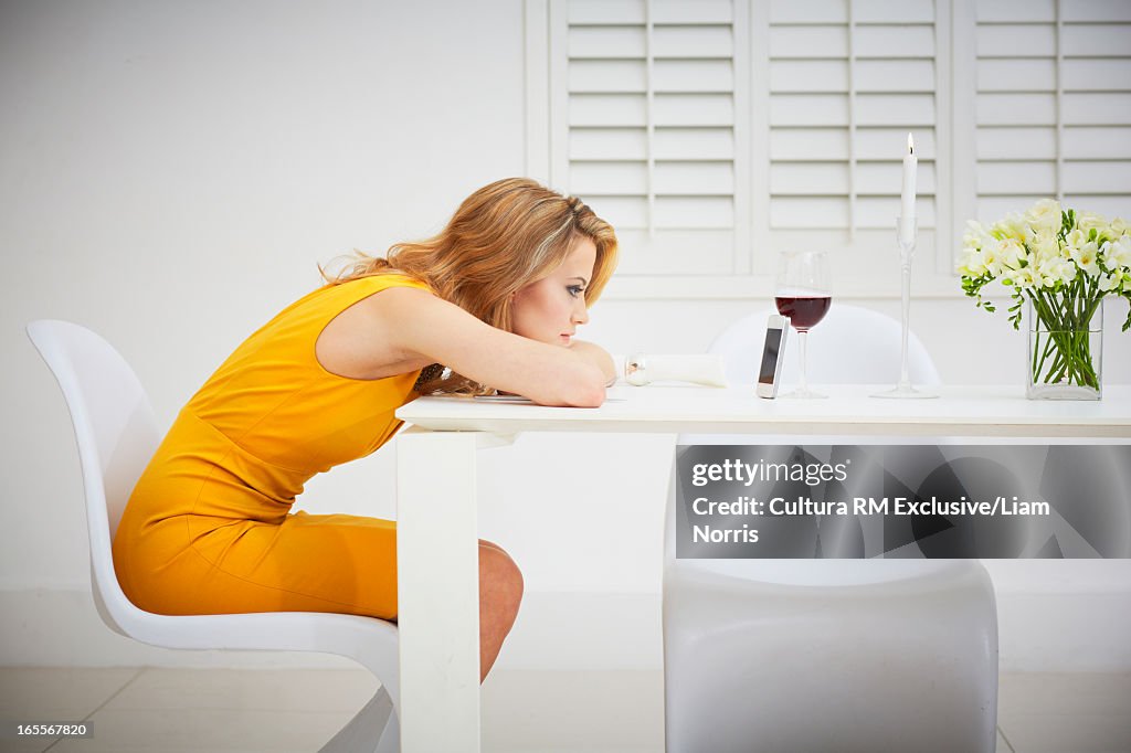 Bored woman using cell phone at table