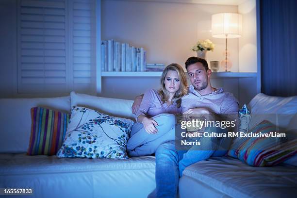 couple watching television on sofa - amor filme de 2012 imagens e fotografias de stock